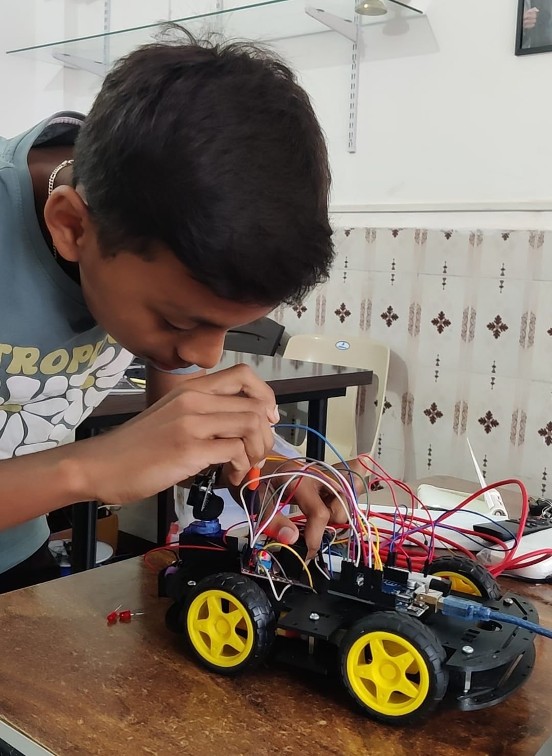 A student writing code for a robot on a laptop in the lab